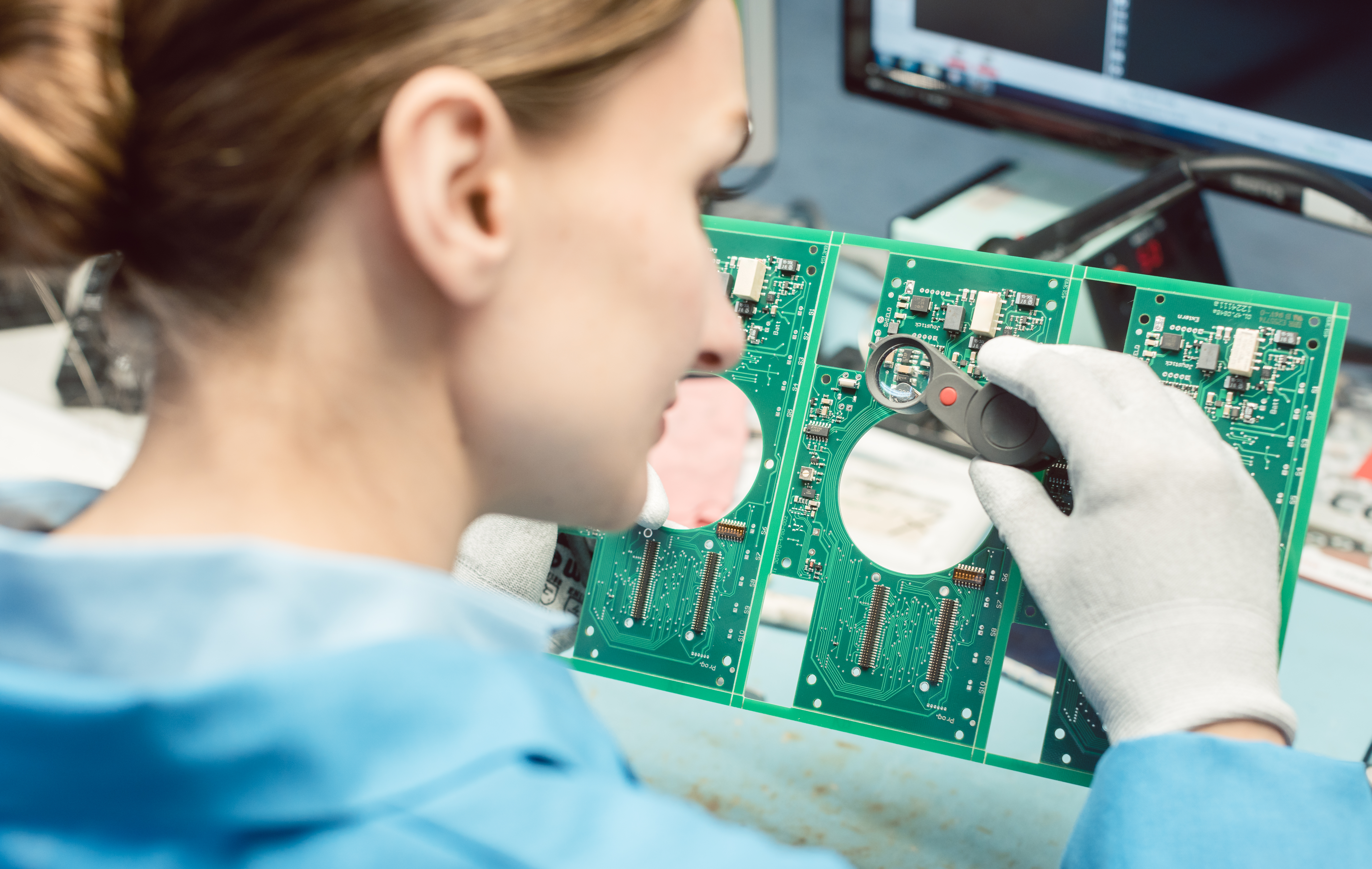 Technician soldering components to a PCB in electronics factory